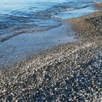 Water lapping on the shore of sand and pebbles